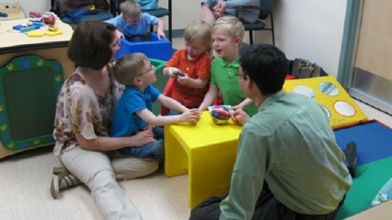 Dr. Lonnie Zwaigenbaum sitting on the floor with children