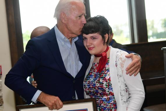 President Biden kissing Sarah Redding on the head as he holds her artwork