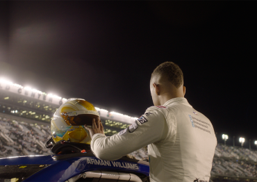 Autistic NASCAR driver Armani Williams looking at the stadium with his helmet on top of his car