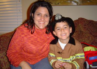 Ethan Hirschberg at age 4 wearing a fire fighter costume next to his mother
