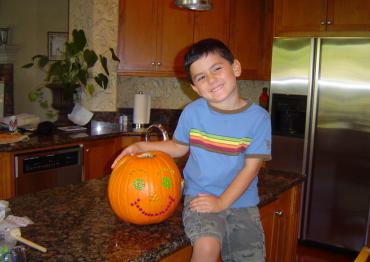 Ethan Hirschberg sitting on the kitchen counter next to a pumpkin when he was 4