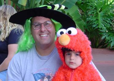 Ethan Hirschberg wearing an Elmo costume and sitting on his dad's lap when he was 2