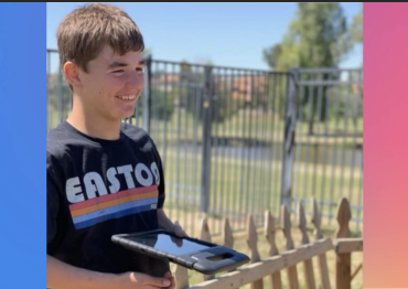 A boy with a shirt that says Easton and a iPad smiles off camera