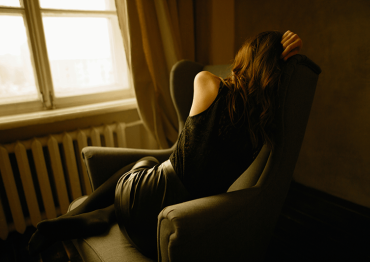 Woman depressed curled up on chair in a dark room