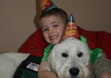 a young boy and his service dog wearing birthday hats