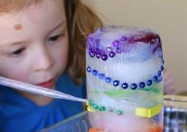 little girl with red hair playing with a rainbow colored sensory ice toy