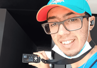 young man wearing Dolphins hat and holding a camera