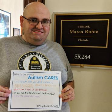 Mike DiMauro holding a sign saying "Why I care about Autism CARES"