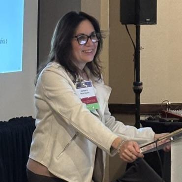 A woman in glasses standing at a podium to present