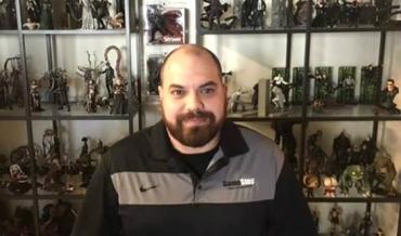 Christopher Hutton in front of a collection of figurines