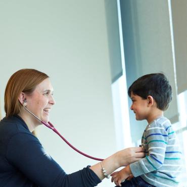 Dr. Amanda Bennett holding a stethoscope to a young boy's chest
