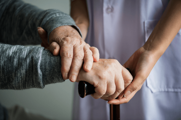 Elderly person holding a walker with assistance from a nurse