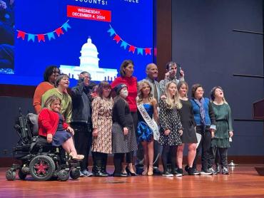 Group of 14 disability advocates standing together on stage