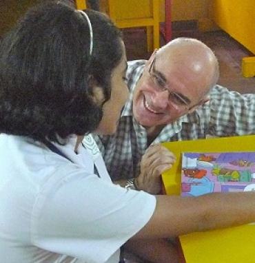 Jonathan Green kneeling down next to a table to talk to a young girl
