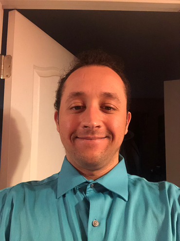 Jordan wearing a blue collared shirt and smiling for a selfie