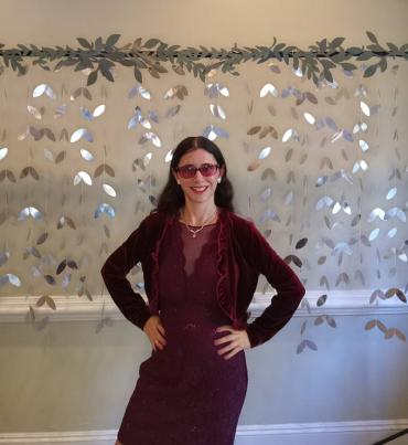 Kelly wearing a red dress in front of a sparkle backdrop