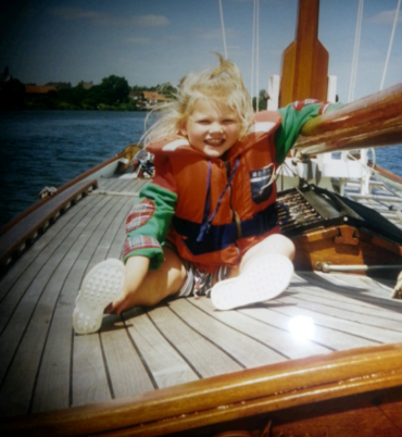Melissa Koole as a child wearing a life jacket on a sailboat
