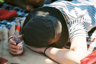 Person passed out holding a bottle of alcohol