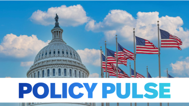 blue sky with clouds behind DC Capitol dome and ten American flags positioned in semi circle on the right
