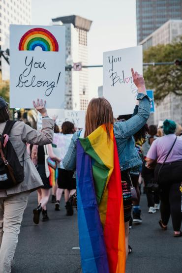 Pride parade goers holding You Belong signs