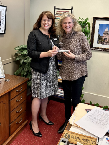 Autism Speaks State Government Affairs Director Christa Stevens presenting Texas State Representative Donna Howard with clear puzzle piece shaped award