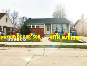 The outside of a house that has a 'proud of our son with autism' sign