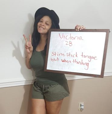 Victoria Handy holding a sign that describes how she stims