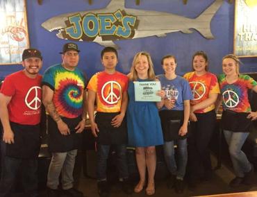 Woman in a blue dress next to Joe's Crab Shack employees