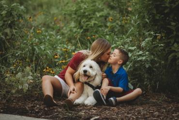 a mother, son and their dog sitting in the forest