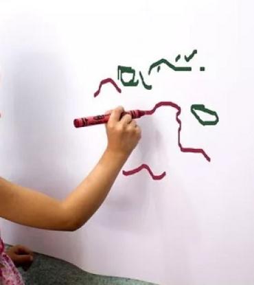 a toddler drawing on a wall with markers
