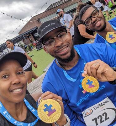 a group of 3 holding up Autism Speaks medals after an endurance event