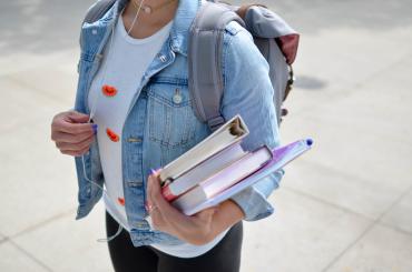 girl student holding books and backpack