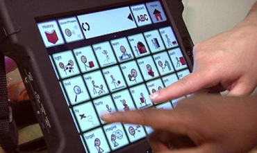 2 hands touching an iPad and using assistive technology to communicate