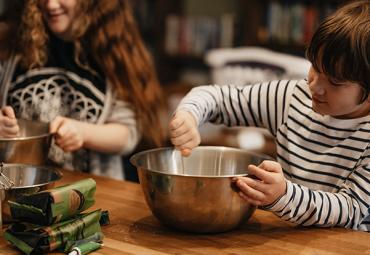 little boy in a striped shirt holding a mixing bowl for baking