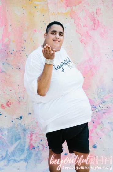 man in a white shirt in front of a watercolor mural