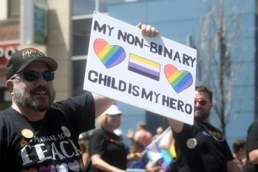 Parent holding My Non-Binary Child Is My Hero sign