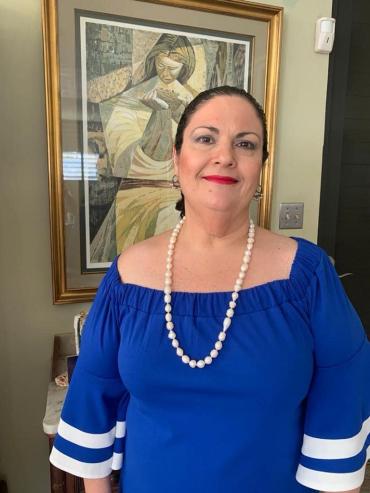 woman in a blue off the shoulder top and pearl necklace