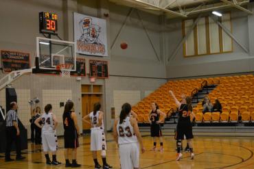 women's basketball game in a gym with orange seats
