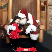 A little girl hugging Santa during a Caring Santa event in 2017