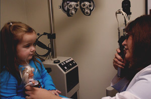 young girl in a blue shirt holding a toy during a vision exam