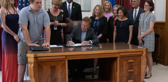 Governor Lamont signing bill and surrounded by advocates
